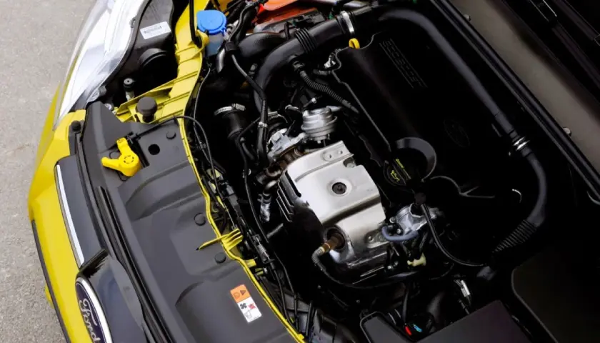 Silnik Ford 1.0 EcoBoost w komorze silnika żółtego samochodu.