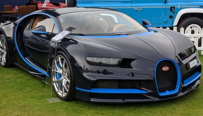 Ciemnoniebieskie Bugatti Chiron z niebieskimi akcentami na trawie.