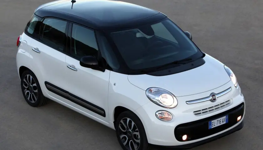 Biały Fiat 500 L z czarnym dachem, zaparkowany na szarym podłożu.