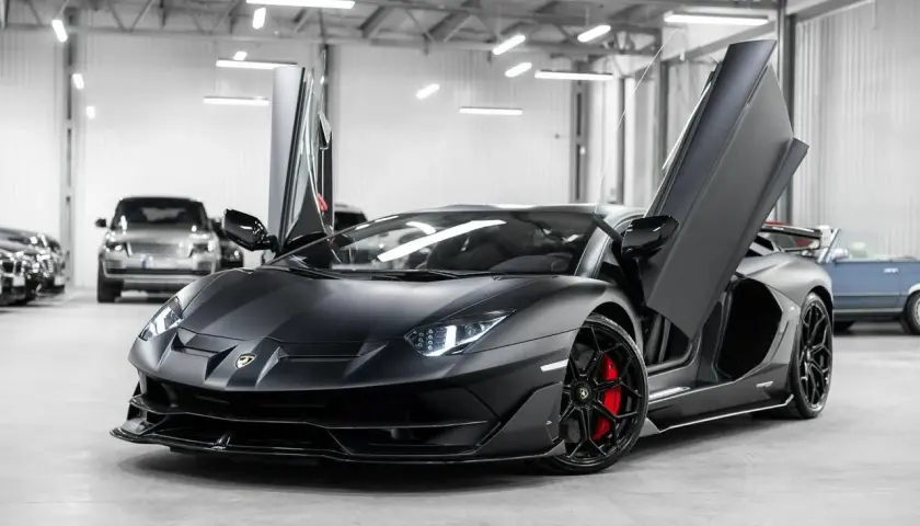 Matowy czarny Lamborghini Aventador SVJ z otwartymi drzwiami. Zastanawiasz się, ile kosztuje Lamborghini Aventador SVJ?