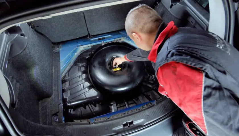 Mechanik sprawdza butlę LPG w bagażniku. Dowiedz się, ile kosztuje legalizacja butli LPG i jakie są wymagania.
