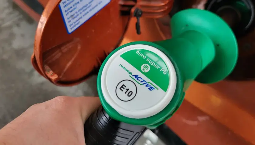Dłoń trzyma zielony pistolet dystrybutora paliwa z oznaczeniami 95 Pb i E10.