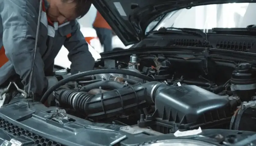 Mechanik pracuje przy silniku, sprawdzając, ile kosztuje serwis olejowo filtrowy.