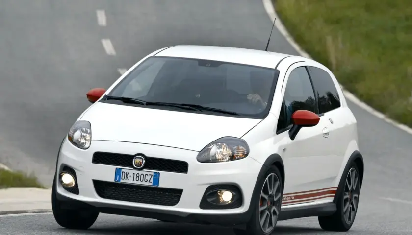 Biały Fiat Grande Punto Abarth na zakręcie drogi.
