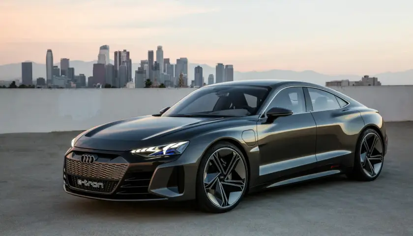 Elegancki Audi e-tron GT na tle miejskiej panoramy o zachodzie słońca.