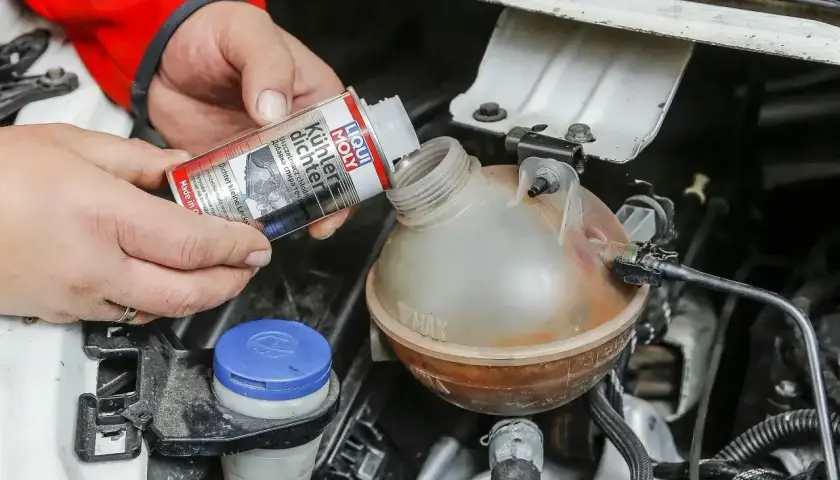 Ręce wlewają Liqui Moly Uszczelniacz chłodnicy do zbiorniczka wyrównawczego.