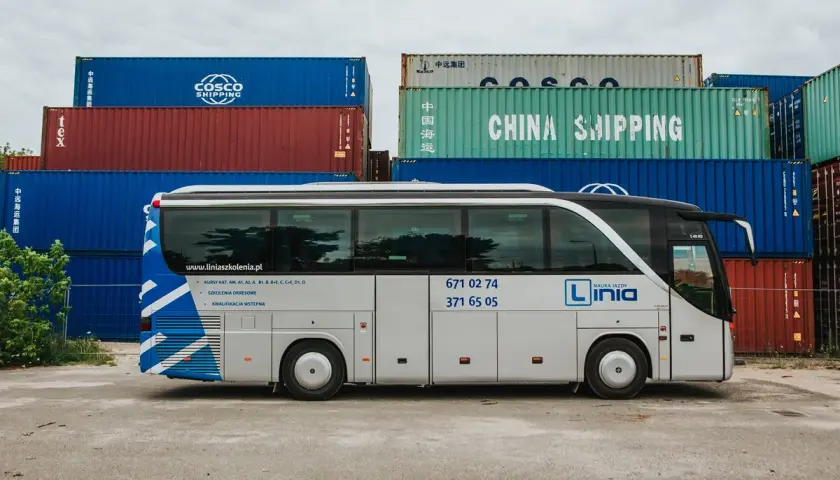 Autobus nauki jazdy "Linia" na tle kontenerów. Oferują kursy na prawo jazdy kategorii AM, A, B1, B, B+E, C, C+E, D1, D.