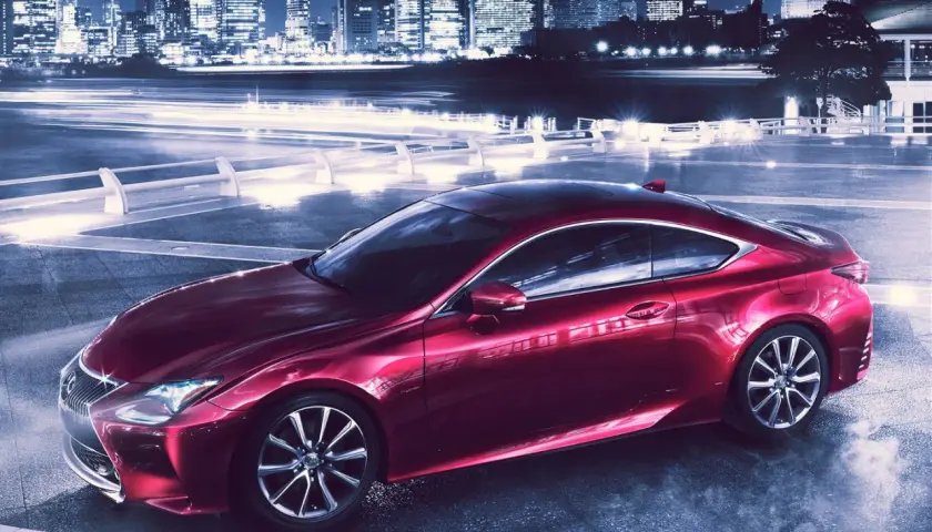 Czerwony Lexus RC 350 na tle nocnego miasta z rozmazanymi światłami.
