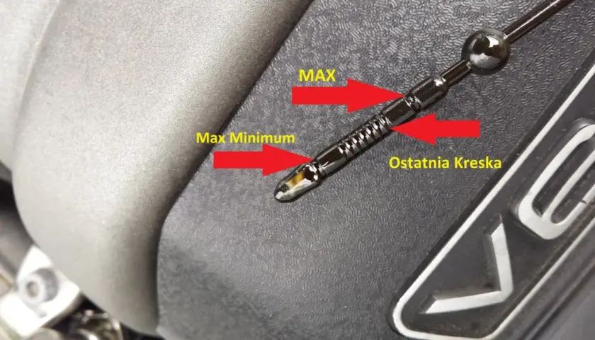 Olej silnikowy na bagnecie znajduje się między oznaczeniami "Max Minimum" a "Ostatnia Kreska", co wskazuje na prawidłowy poziom oleju.