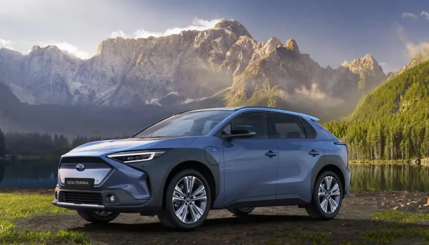 Niebieski Subaru Solterra na tle gór i jeziora.
