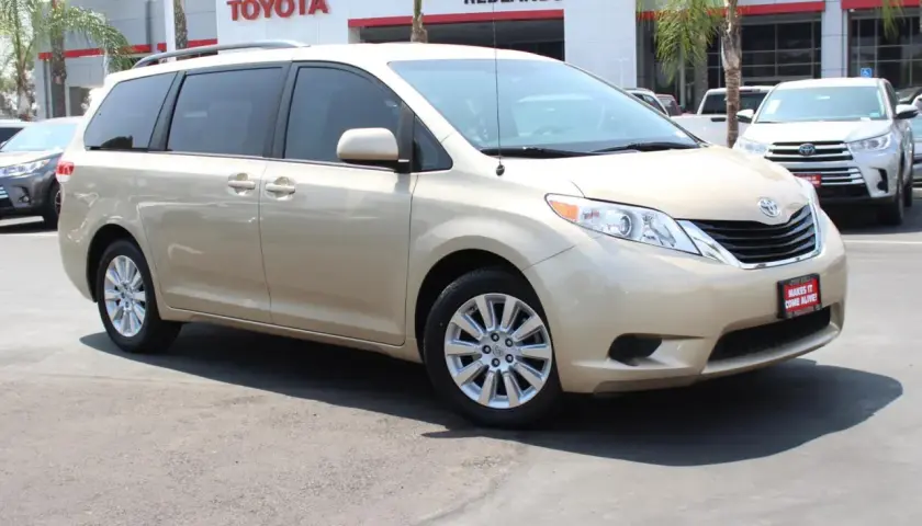 Złoty minivan Toyota Sienna zaparkowany przed salonem Toyoty.