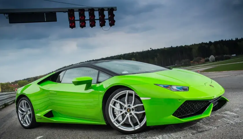 Zielony Lamborghini Huracan na torze wyścigowym, gotowy do startu pod światłami.