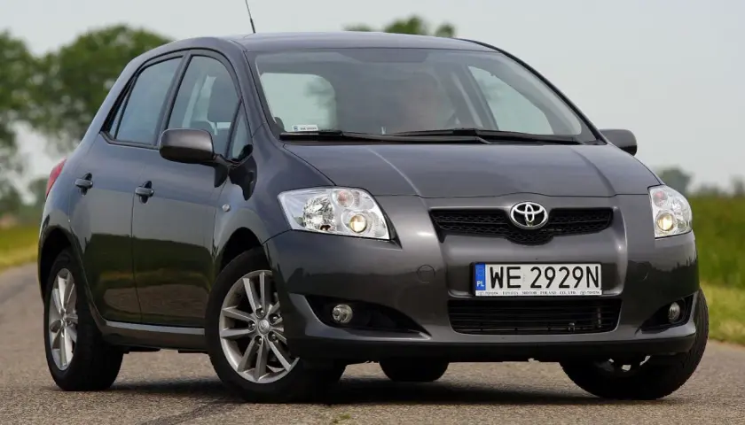 Szary samochód Toyota Auris na drodze, przód auta z bliska.