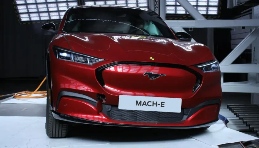 Czerwony Ford Mustang Mach-E w studiu z tabliczką "MACH-E".