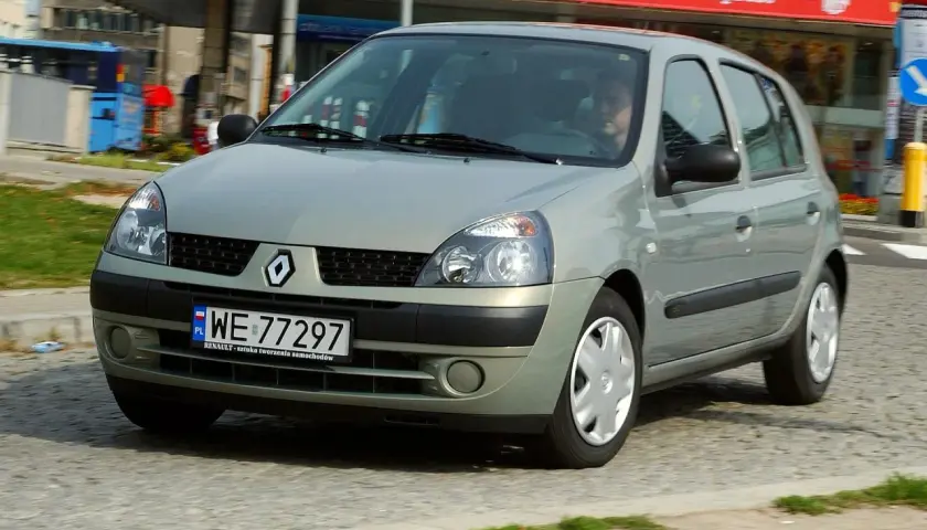Srebrny Renault Clio 2 z polskimi tablicami rejestracyjnymi WE 77297 jedzie po miejskiej ulicy.