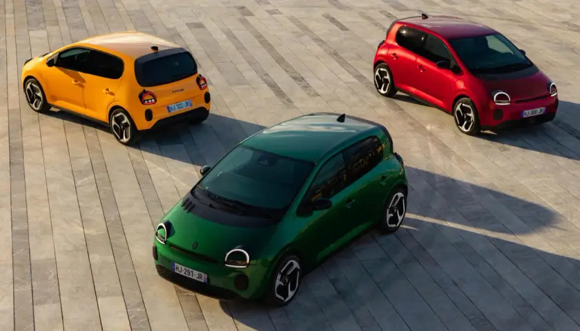 Trzy kolorowe Renault Twingo 2: zielone, żółte i czerwone, stoją na betonowej nawierzchni.