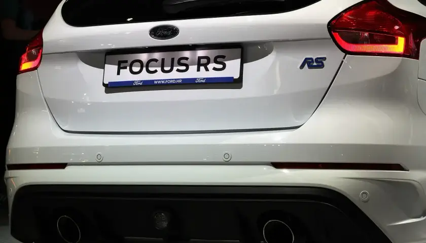 Tył białego Forda Focus RS z widocznymi światłami, napisem "FOCUS RS" i podwójnymi końcówkami wydechu.