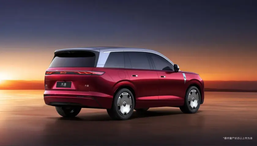 Czerwony elektryczny SUV BYD Tang z dwukolorowym nadwoziem na tle zachodzącego słońca.
