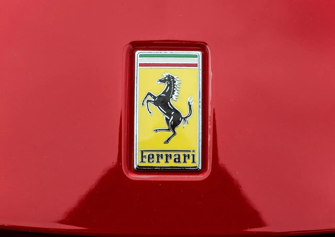 Jaki znaczek ma Ferrari? Czarny koń na żółtym tle, z napisem Ferrari.