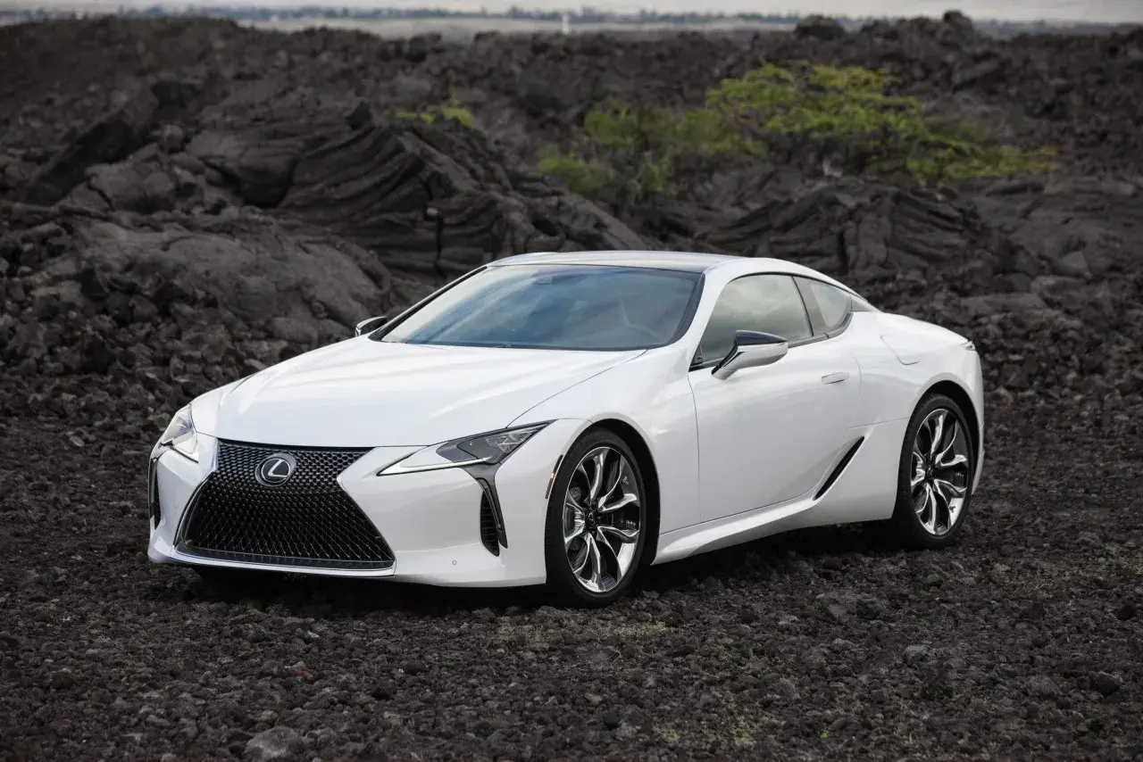 Biały Lexus LC 500 na tle wulkanicznych skał.