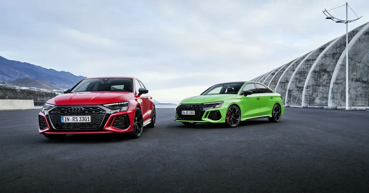 Dwa Audi RS 3 Sportback: czerwone i zielone, zaparkowane na zewnątrz.