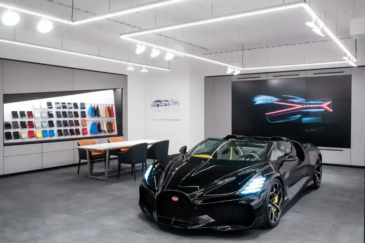 Czarny Bugatti w salonie, obok próbek skór i ekranu z grafiką. Ile jest Bugatti w Polsce? Trudno powiedzieć, ale ten wygląda na pierwszy.