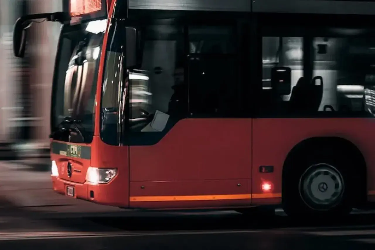 Czerwony autobus miejski w ruchu. Zastanawiasz się nad prawem jazdy kat D cena?