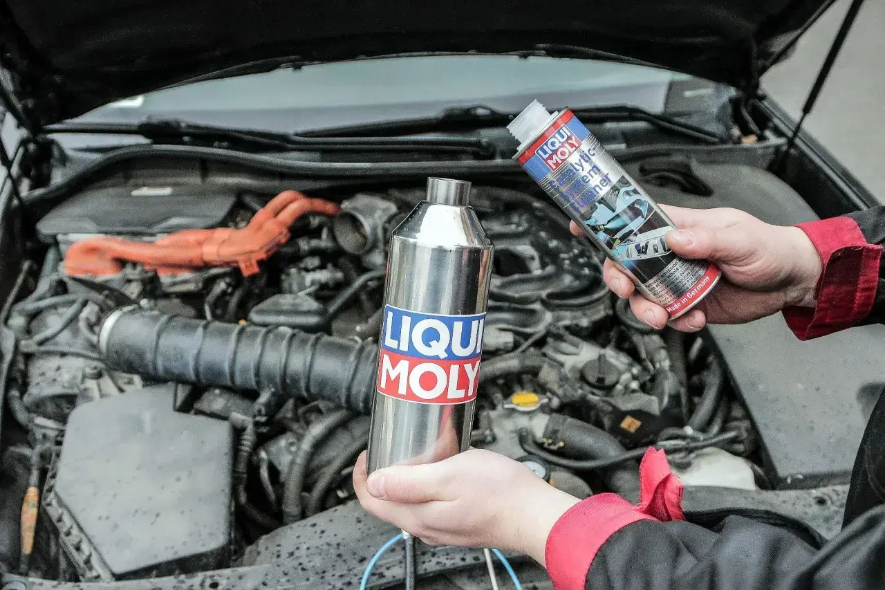 Ręce trzymają preparat do czyszczenia katalizatora diesel marki Liqui Moly. W tle widać silnik samochodu.