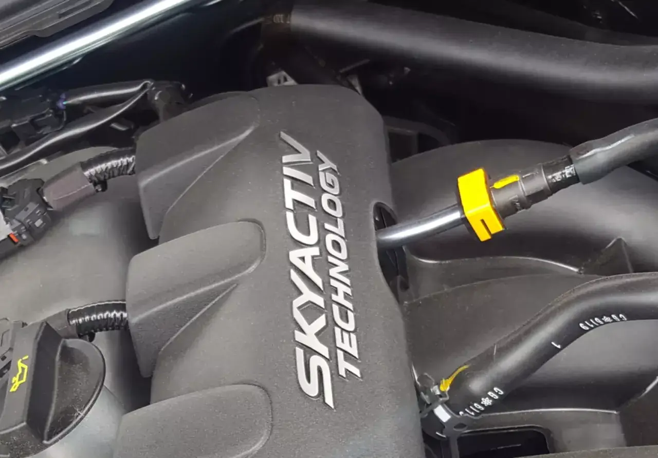 Silnik SKYACTIV TECHNOLOGY, jeden z najlepszych silników benzynowych, z widocznymi przewodami i złączkami.