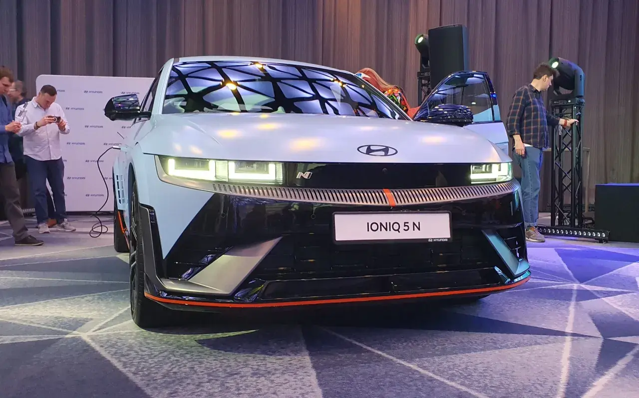 Hyundai IONIQ 5 N na prezentacji, z otwartymi drzwiami, w tle ludzie i logo Hyundai.