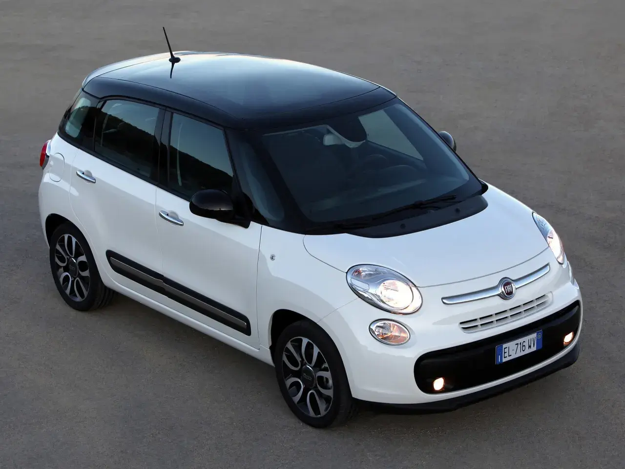 Biały Fiat 500 L z czarnym dachem, zaparkowany na szarym podłożu.
