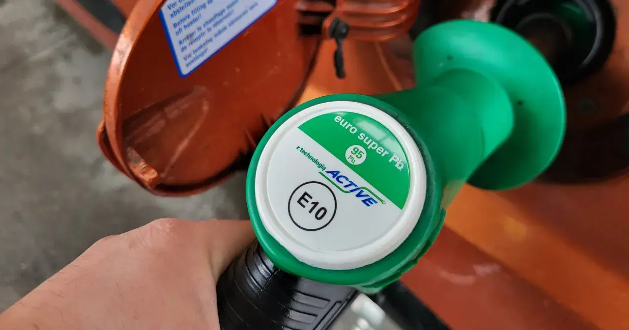 Dłoń trzyma zielony pistolet dystrybutora paliwa z oznaczeniami 95 Pb i E10.