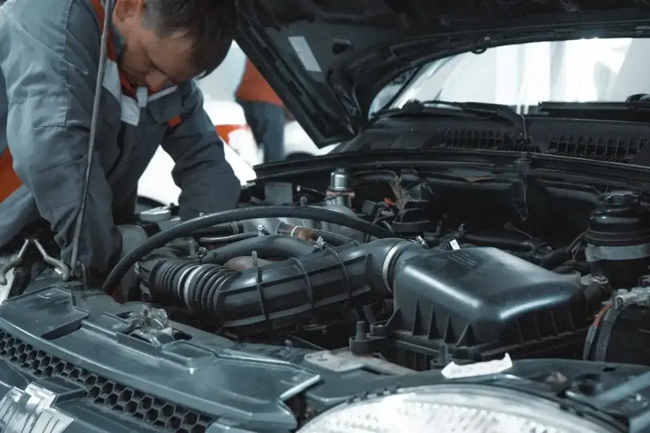 Mechanik pracuje przy silniku, sprawdzając, ile kosztuje serwis olejowo filtrowy.