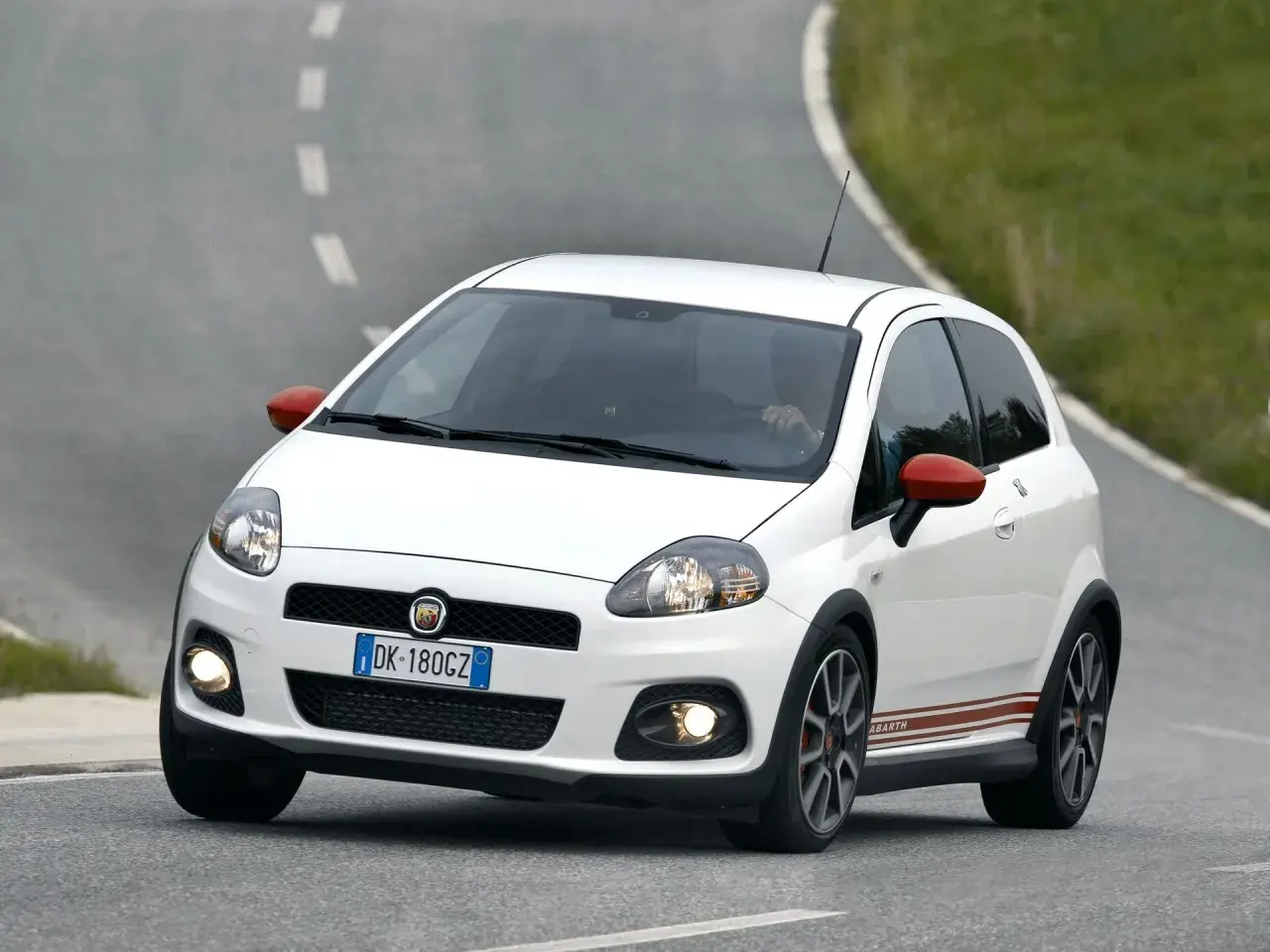 Biały Fiat Grande Punto Abarth na zakręcie drogi.