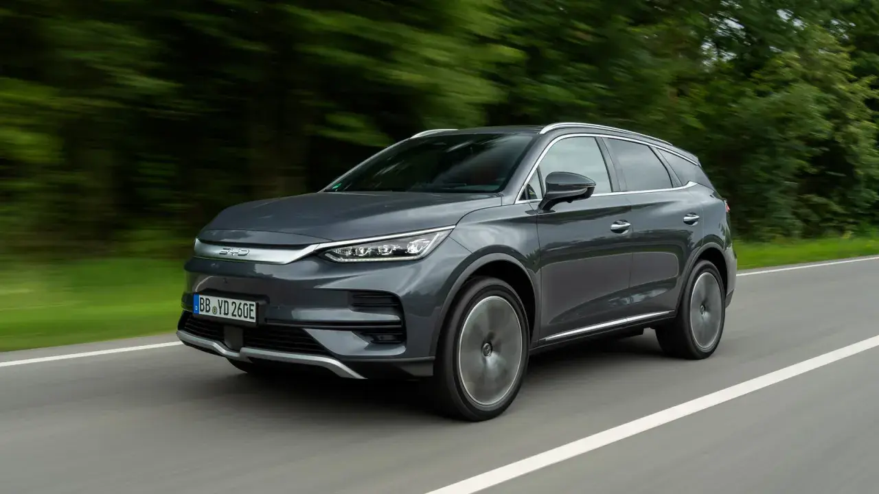 Szary SUV BYD Tang w ruchu drogowym, z rozmytym tłem drzew.