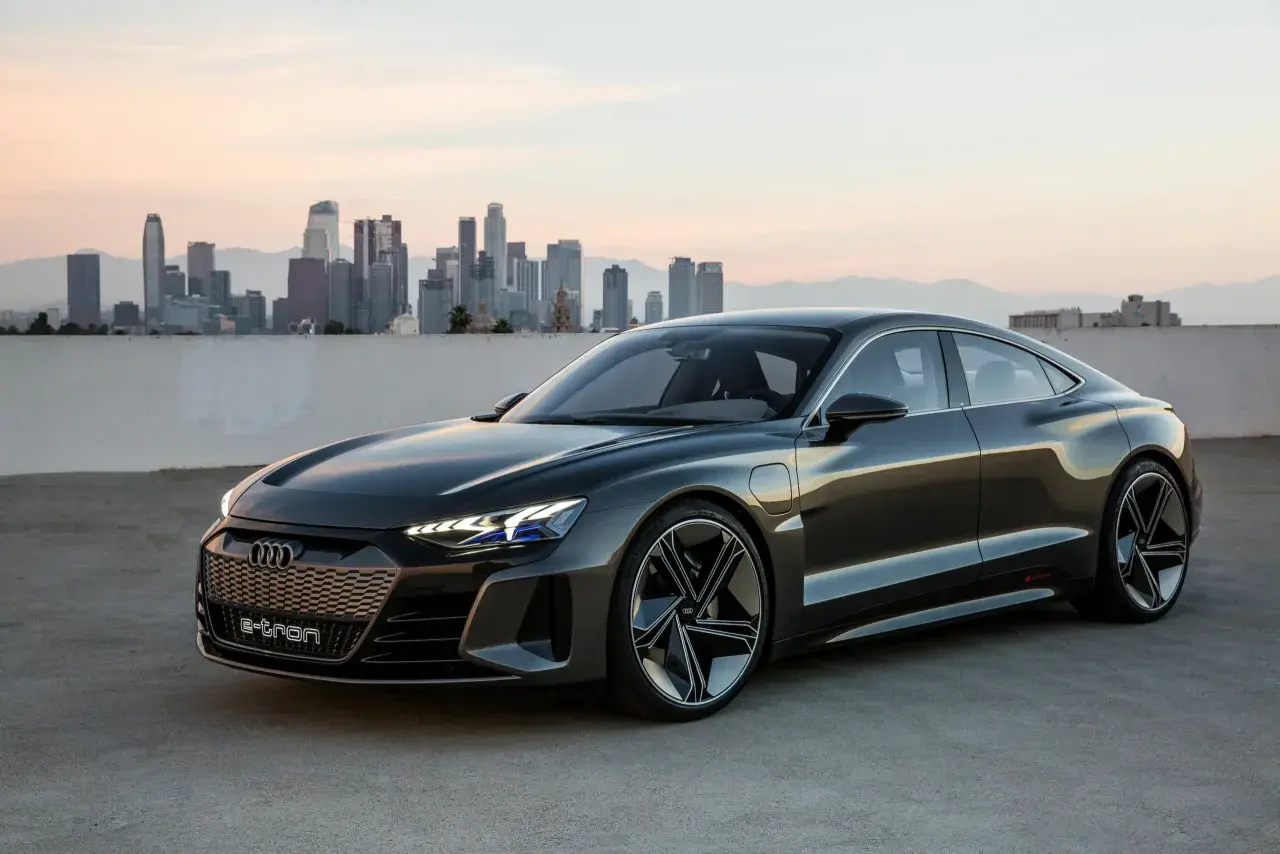 Elegancki Audi e-tron GT na tle miejskiej panoramy o zachodzie słońca.