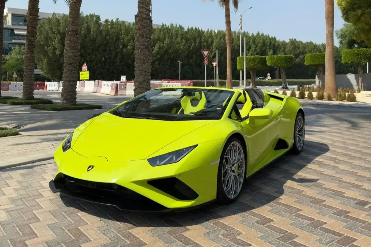 Jaskrawożółte Lamborghini z otwartym dachem, zaparkowane na brukowanej nawierzchni. Kto jest właścicielem tego cacka?