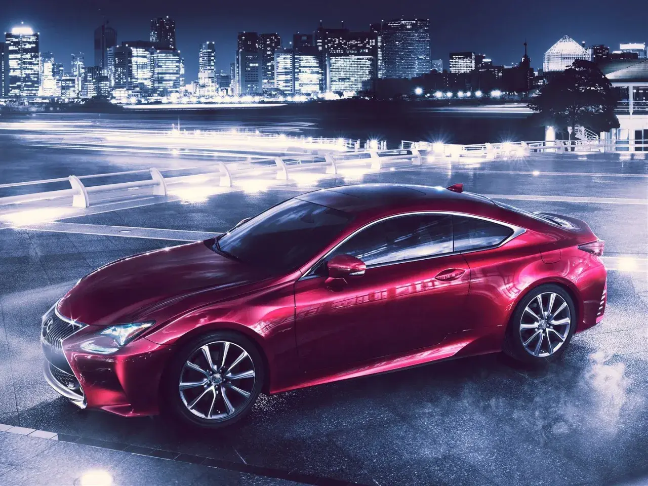 Czerwony Lexus RC 350 na tle nocnego miasta z rozmazanymi światłami.