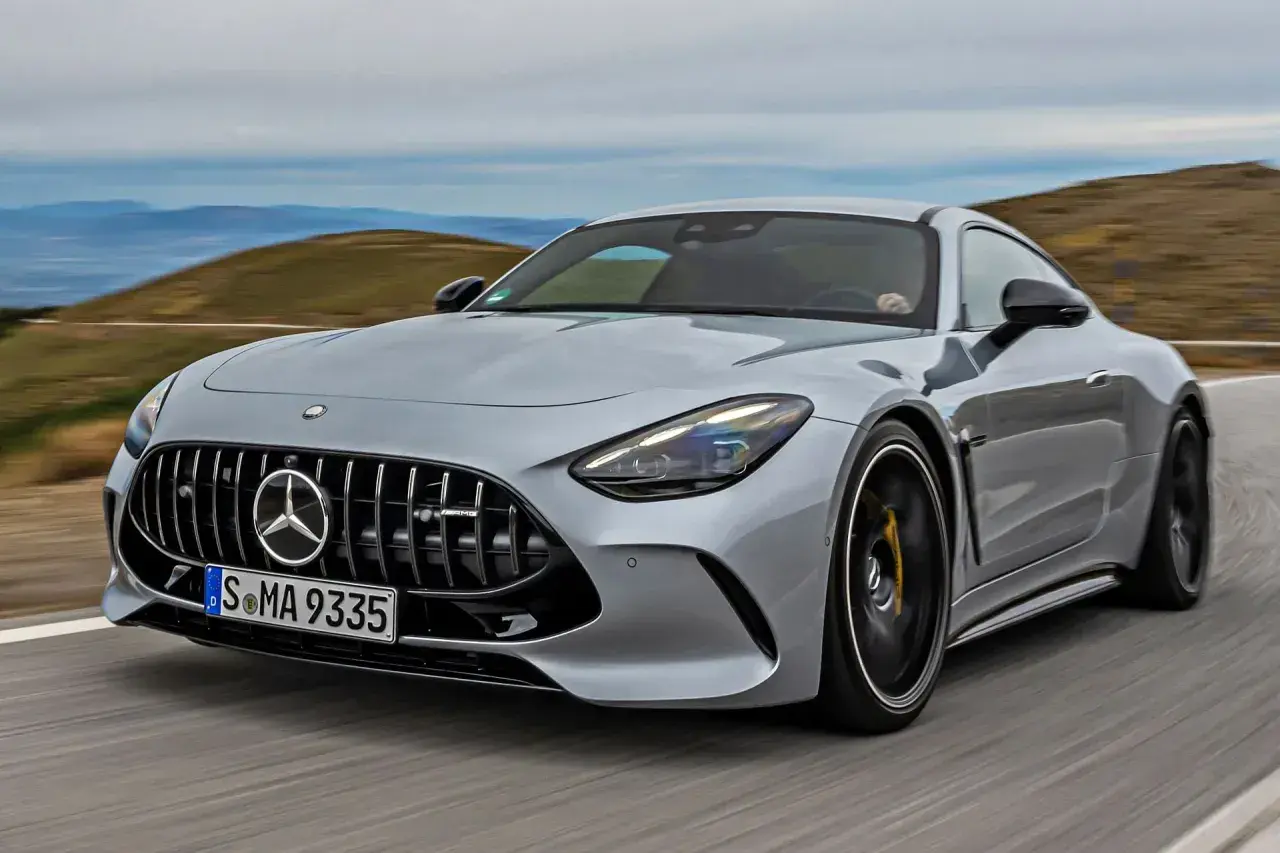 Srebrny Mercedes-AMG GT sunie po krętej drodze, ukazując swoją sportową sylwetkę i potężny grill.