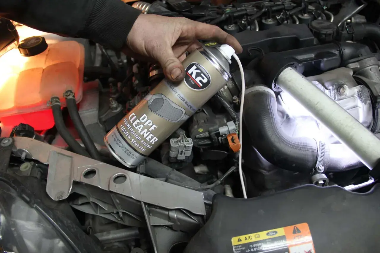 Ręka trzyma puszkę płynu do wypalania DPF, który pomaga oczyścić filtr cząstek stałych w silniku.