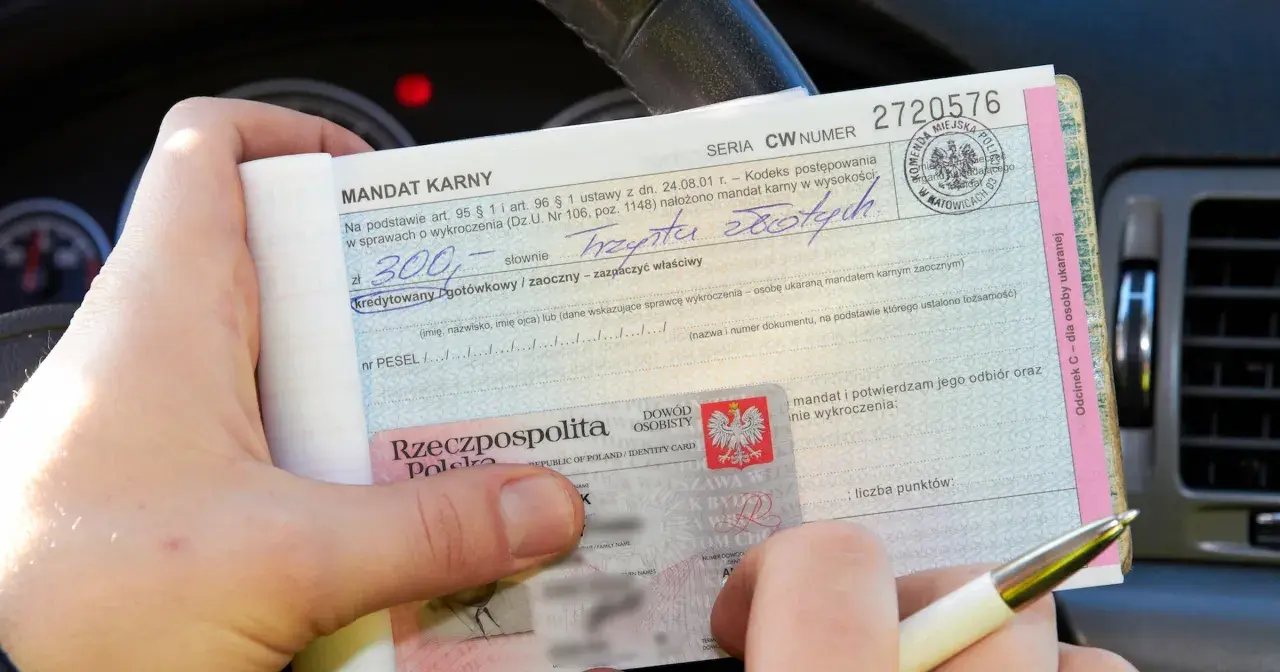 Mandat karny na 300 zł za wykroczenie. W tle widać fragment deski rozdzielczej samochodu, sugerujący, że zdarzenie miało miejsce na skrzyżowaniu.