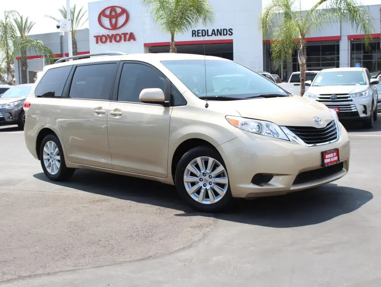 Złoty minivan Toyota Sienna zaparkowany przed salonem Toyoty.