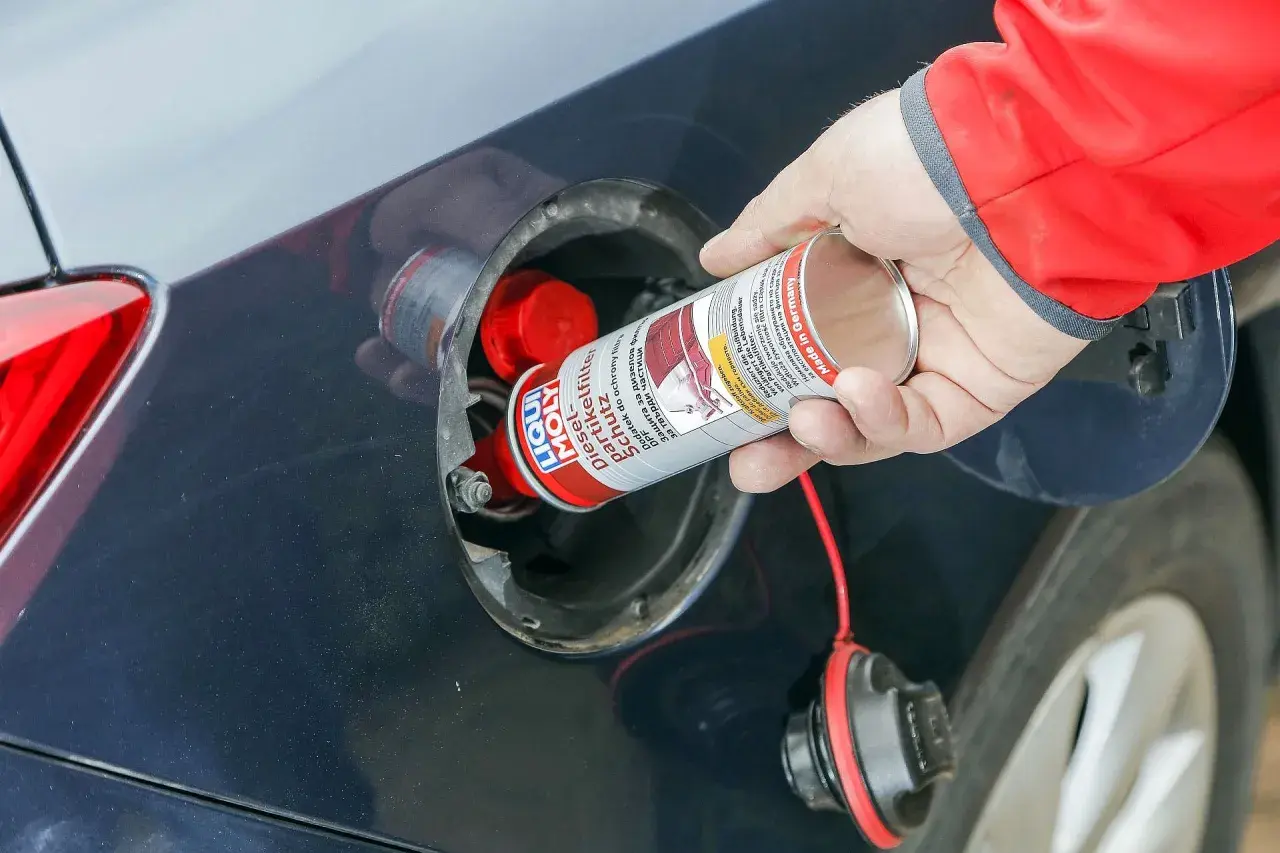 Ręka wlewa dodatek do diesla DPF do baku samochodu. Preparat chroni filtr cząstek stałych.