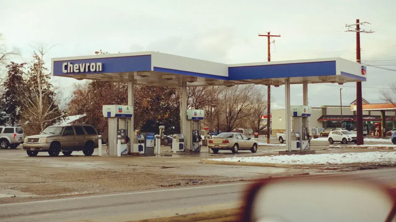Stacja Chevron, samochody na zimowym parkingu. Zastanawiasz się, ile kosztuje jeden galon benzyny w USA?