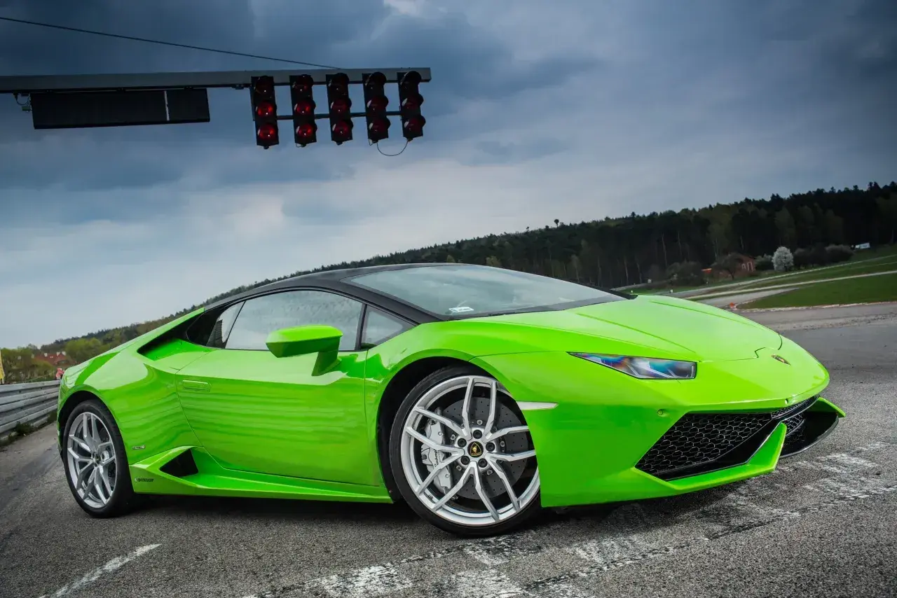 Zielony Lamborghini Huracan na torze wyścigowym, gotowy do startu pod światłami.