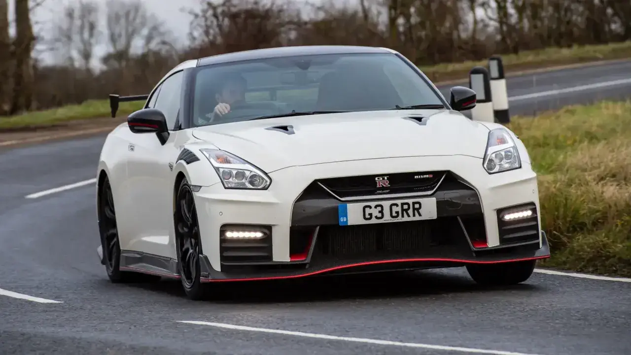 Biały Nissan GT-R Nismo z czerwonymi akcentami pędzi po drodze.