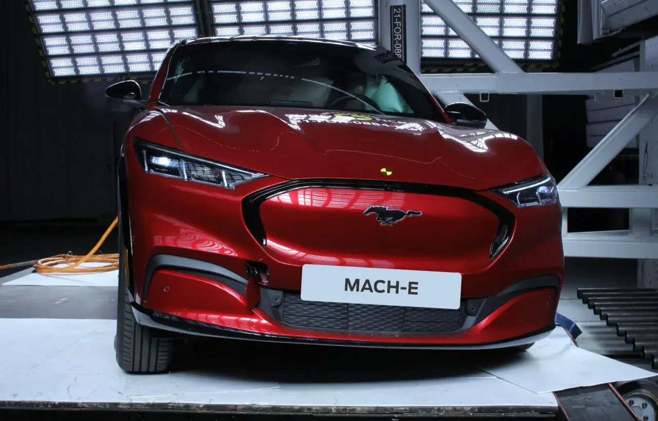 Czerwony Ford Mustang Mach-E w studiu z tabliczką "MACH-E".