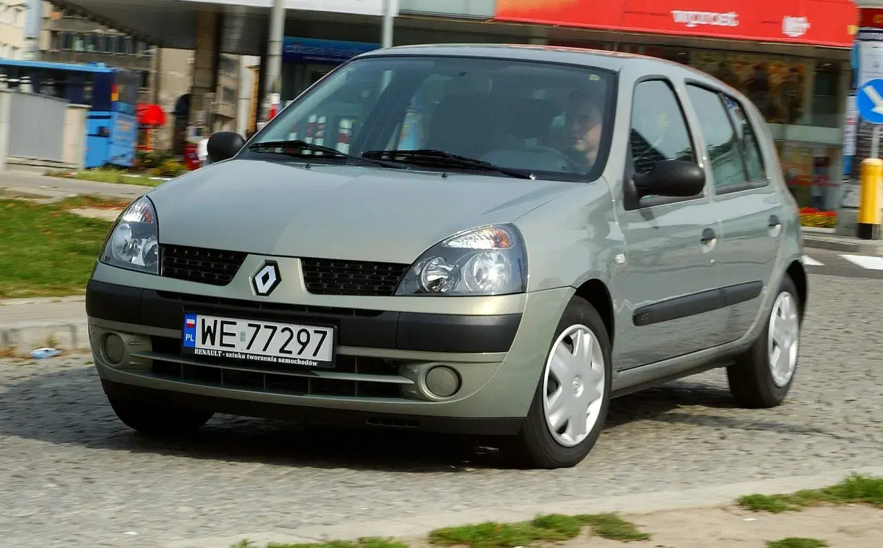 Srebrny Renault Clio 2 z polskimi tablicami rejestracyjnymi WE 77297 jedzie po miejskiej ulicy.