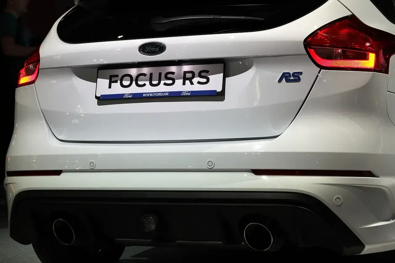 Tył białego Forda Focus RS z widocznymi światłami, napisem "FOCUS RS" i podwójnymi końcówkami wydechu.