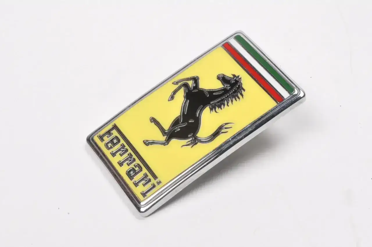 Oto jak wygląda znaczek Ferrari: żółte tło, czarny koń w galopie, napis